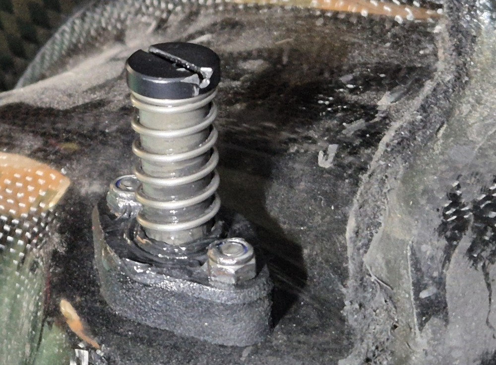 Jousituksen yläläpivienti ja palautusjousi. Oikealla karvamato on sähköjohto ja sen kiinnitys koriin.